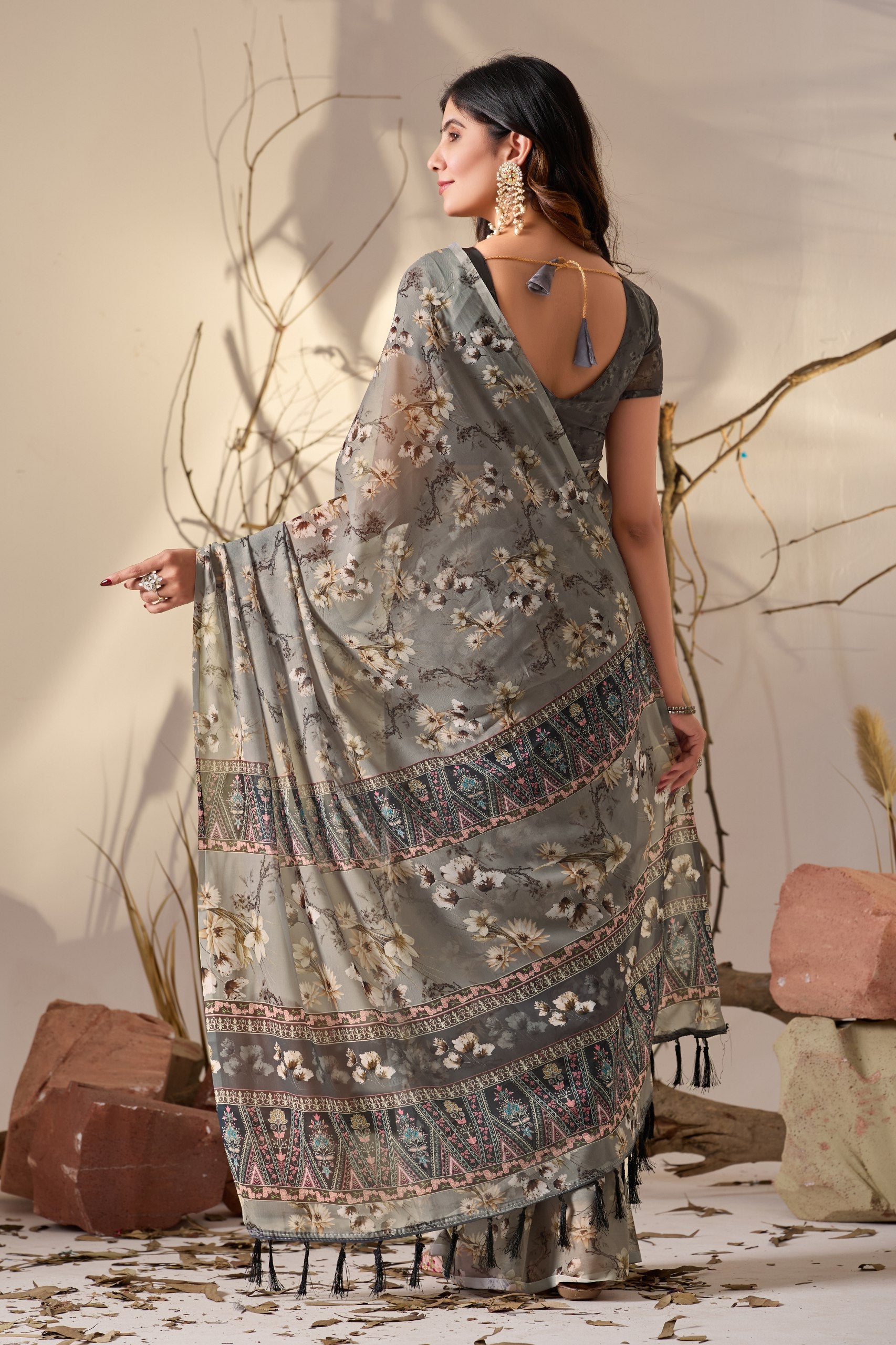 Soft Georgette Saree in Muted Grey Base Adorned with All-Over Floral Digital Print and Enhanced with Ornate Tribal-Style Patterned Pallu Featuring Pink, Black & Teal Accents + Elegant Black Tassel Detailing