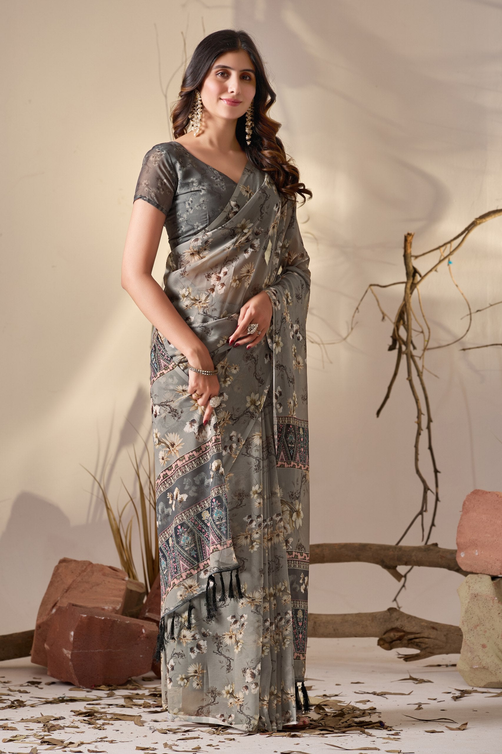 Soft Georgette Saree in Muted Grey Base Adorned with All-Over Floral Digital Print and Enhanced with Ornate Tribal-Style Patterned Pallu Featuring Pink, Black & Teal Accents + Elegant Black Tassel Detailing
