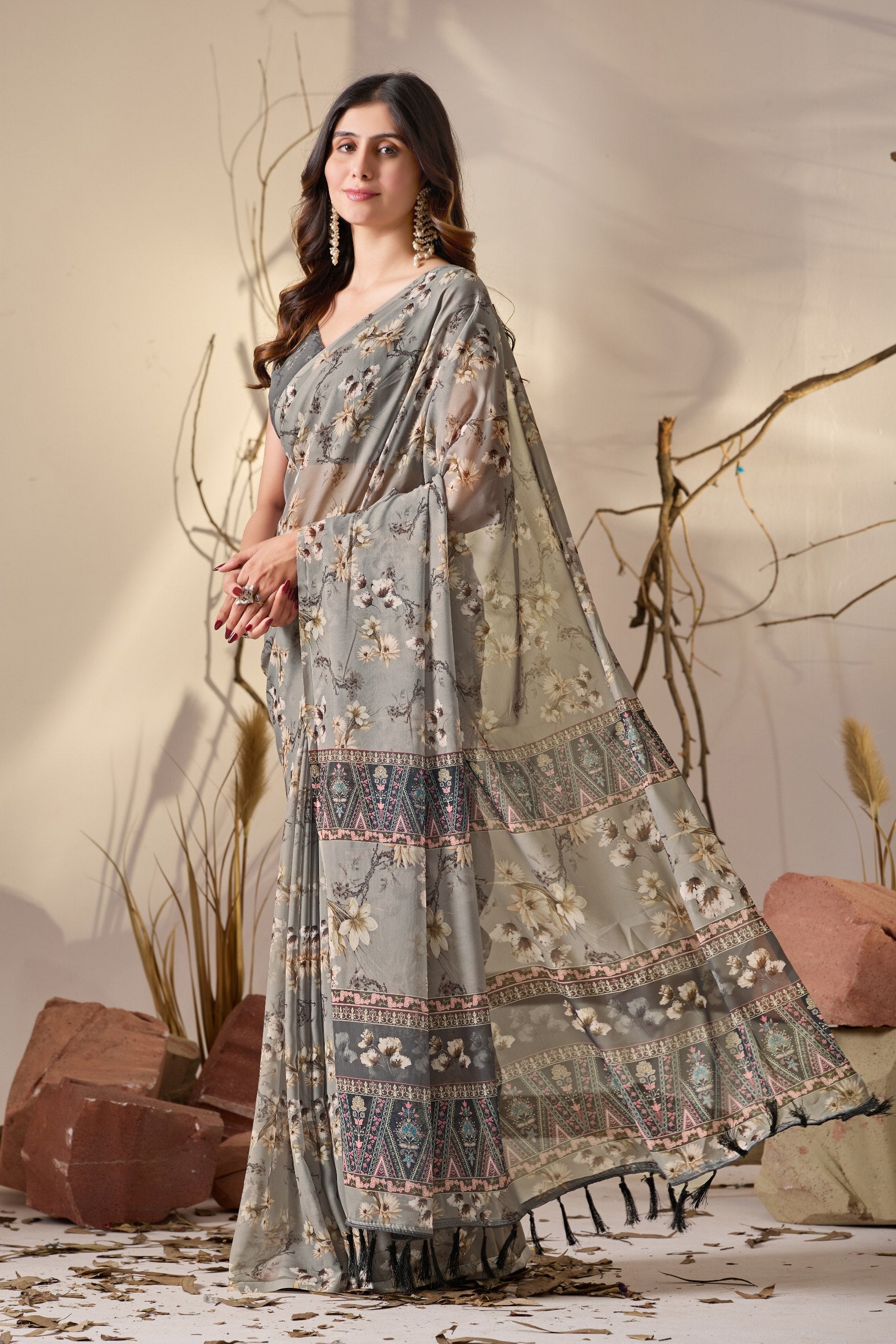Soft Georgette Saree in Muted Grey Base Adorned with All-Over Floral Digital Print and Enhanced with Ornate Tribal-Style Patterned Pallu Featuring Pink, Black & Teal Accents + Elegant Black Tassel Detailing