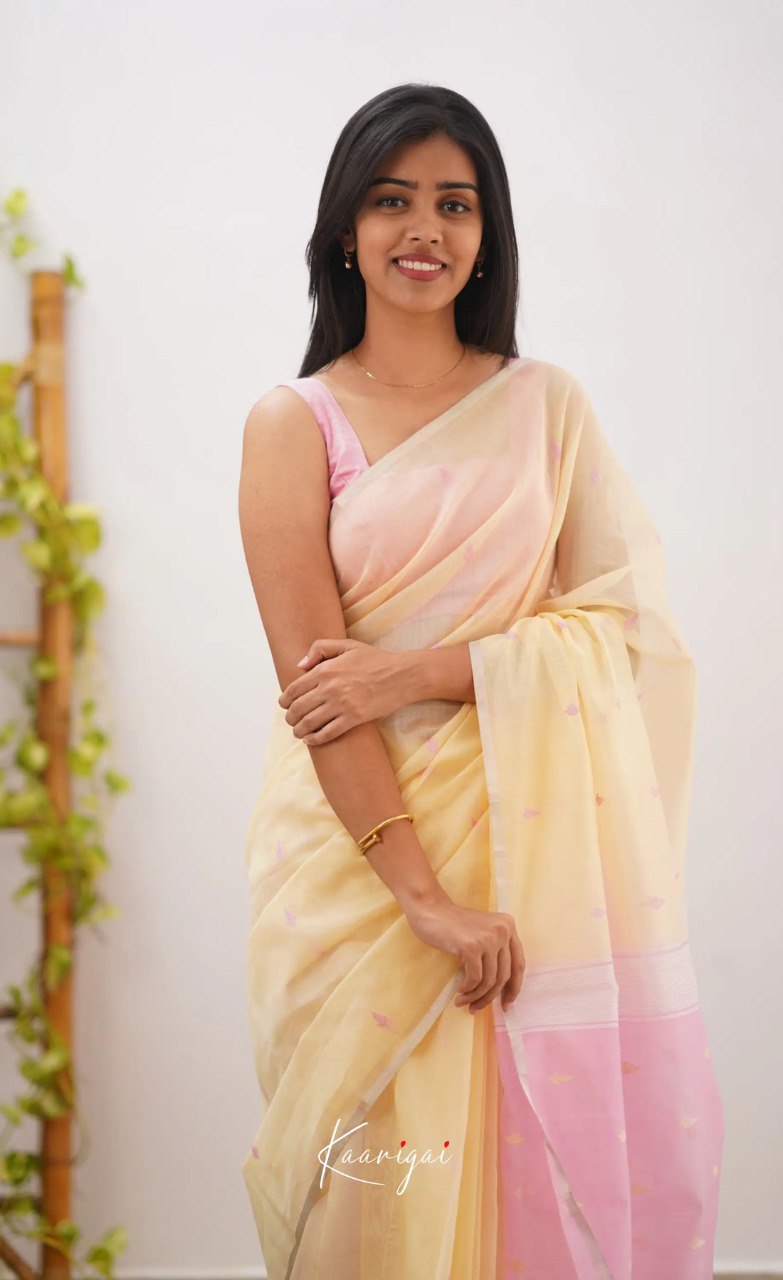 Woman wearing a light yellow and pink saree with a white background